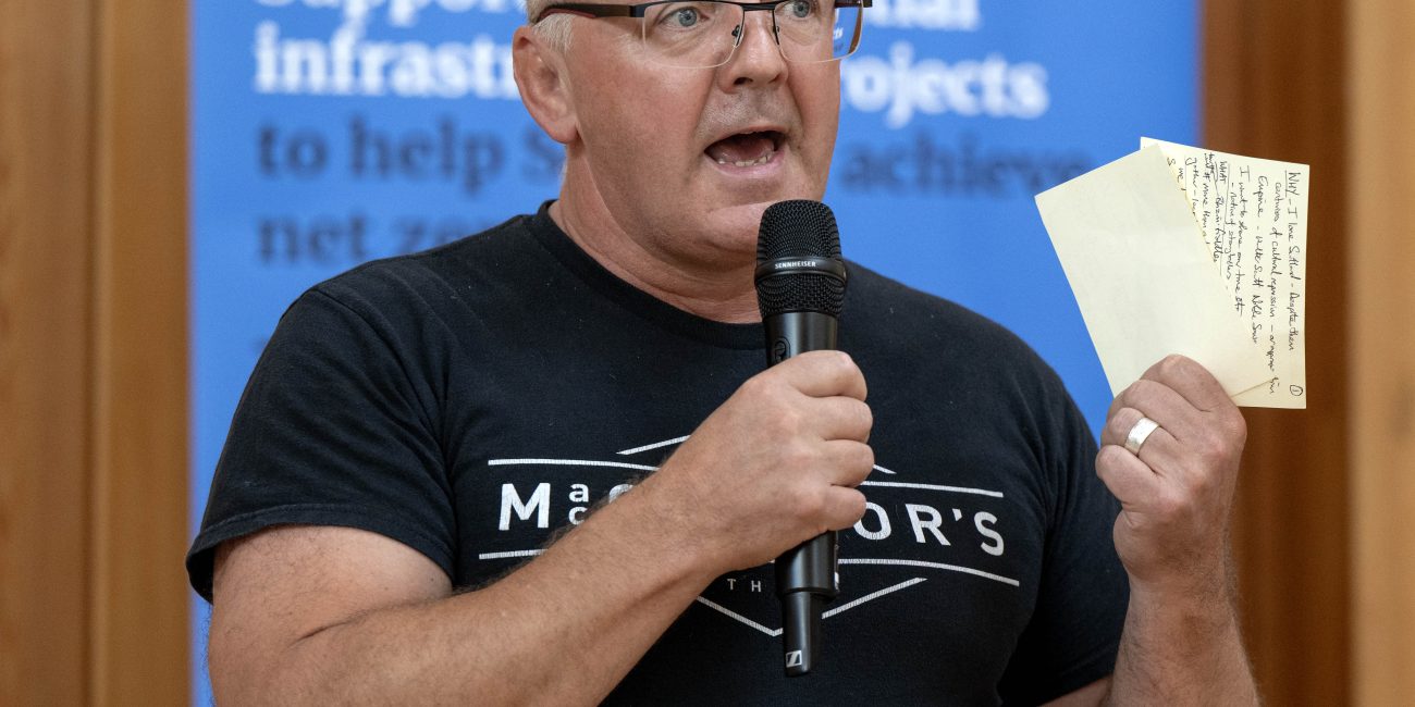Person giving speech with microphone and holding notes