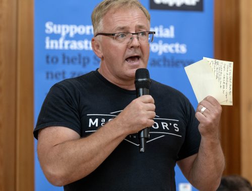 Person giving speech with microphone and holding notes