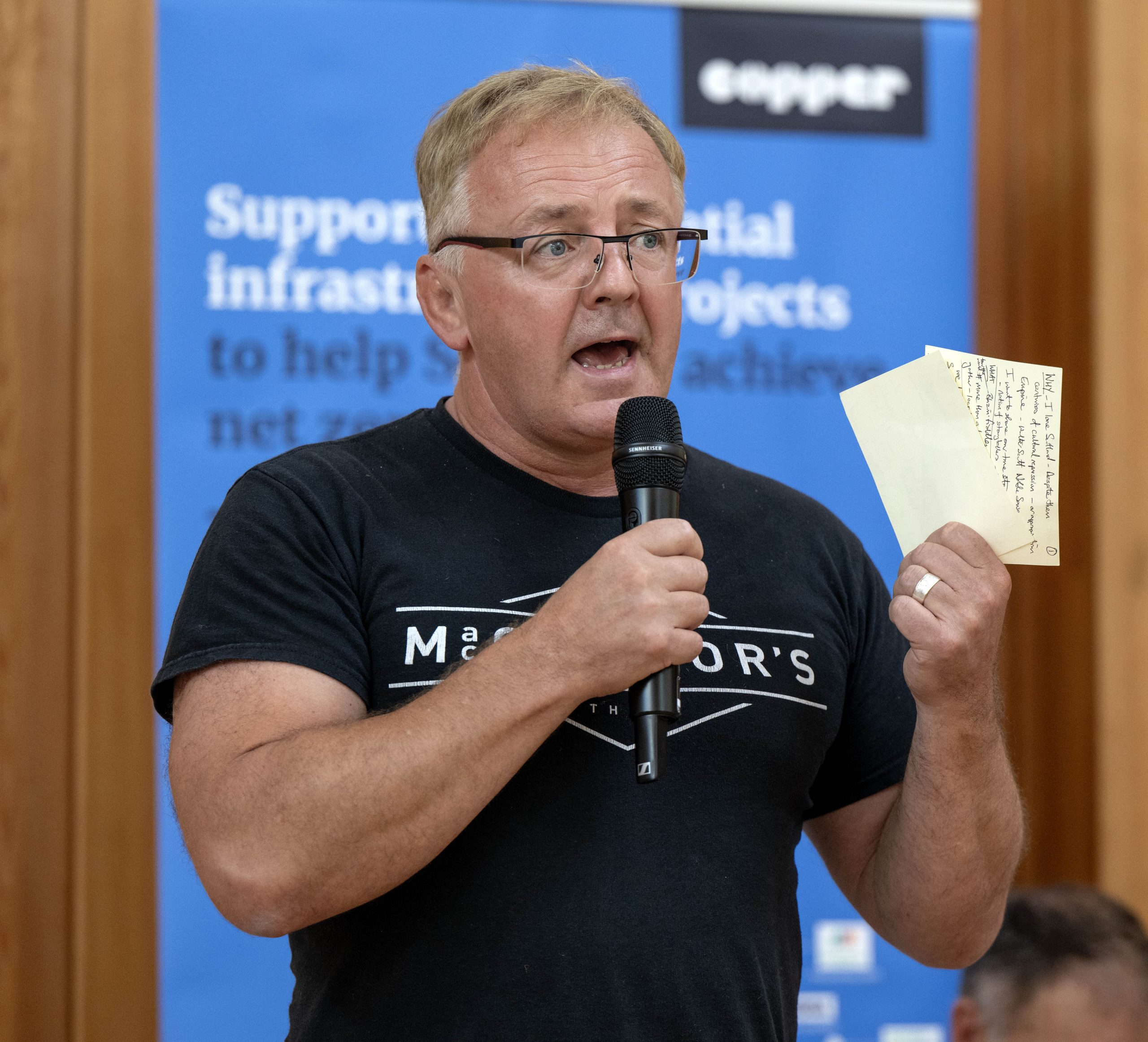 Person giving speech with microphone and holding notes